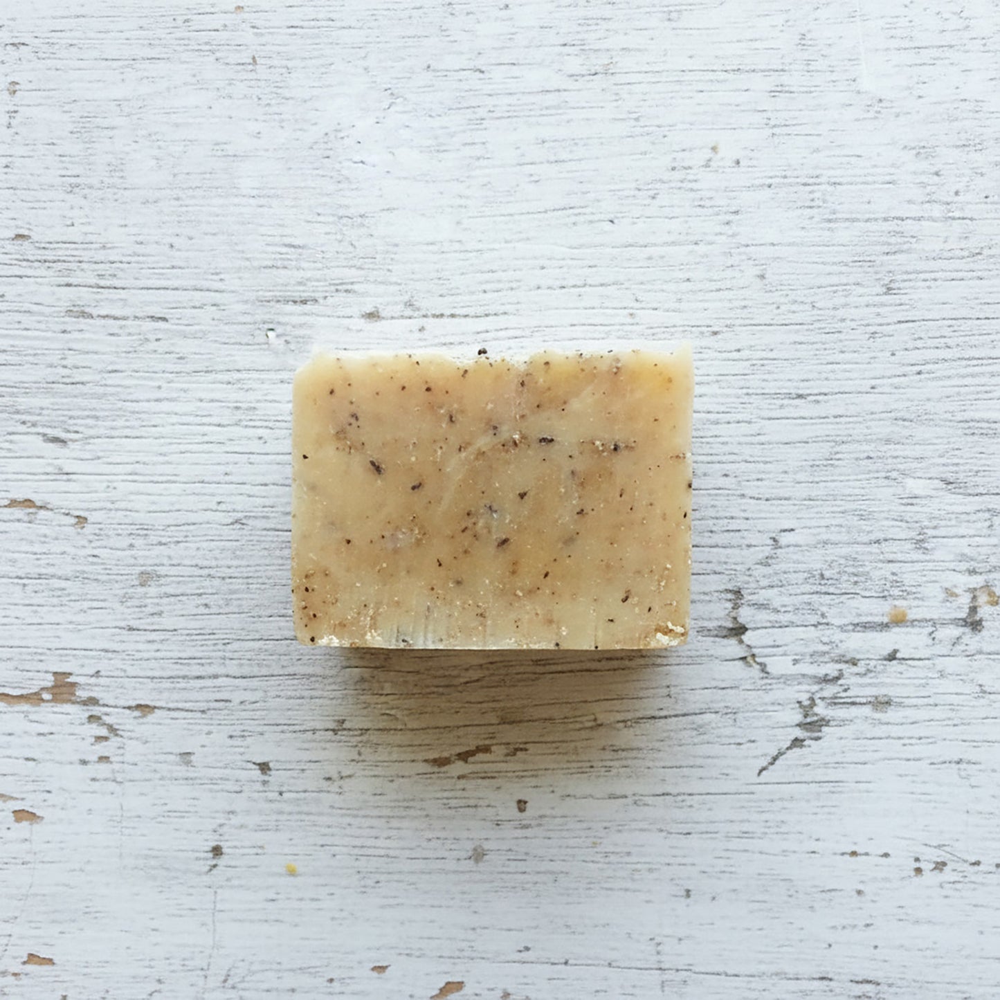 Bar of soap with specks on a textured white surface