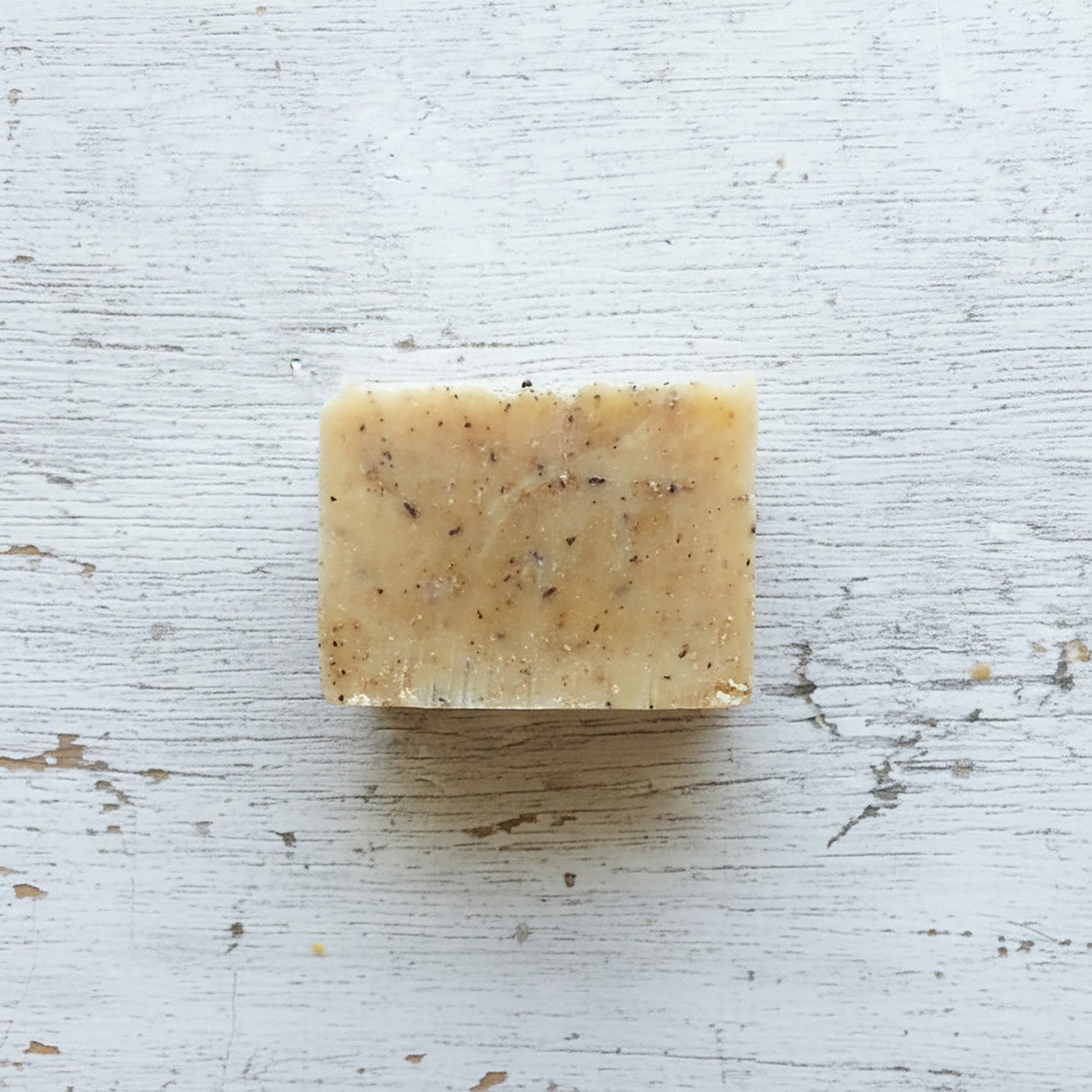 Bar of soap with specks on a textured white surface