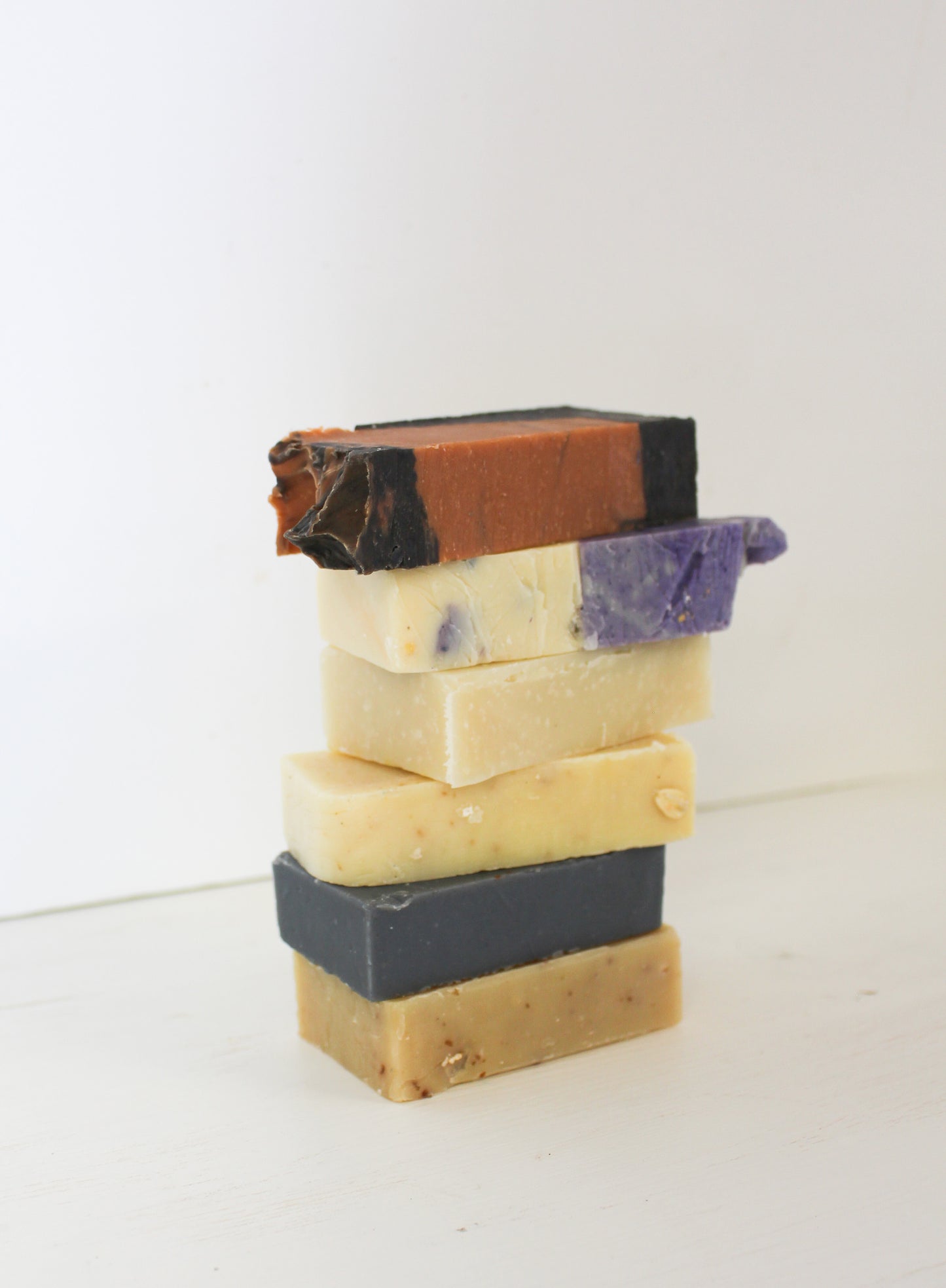 Stack of five different colored soap bars on a white background