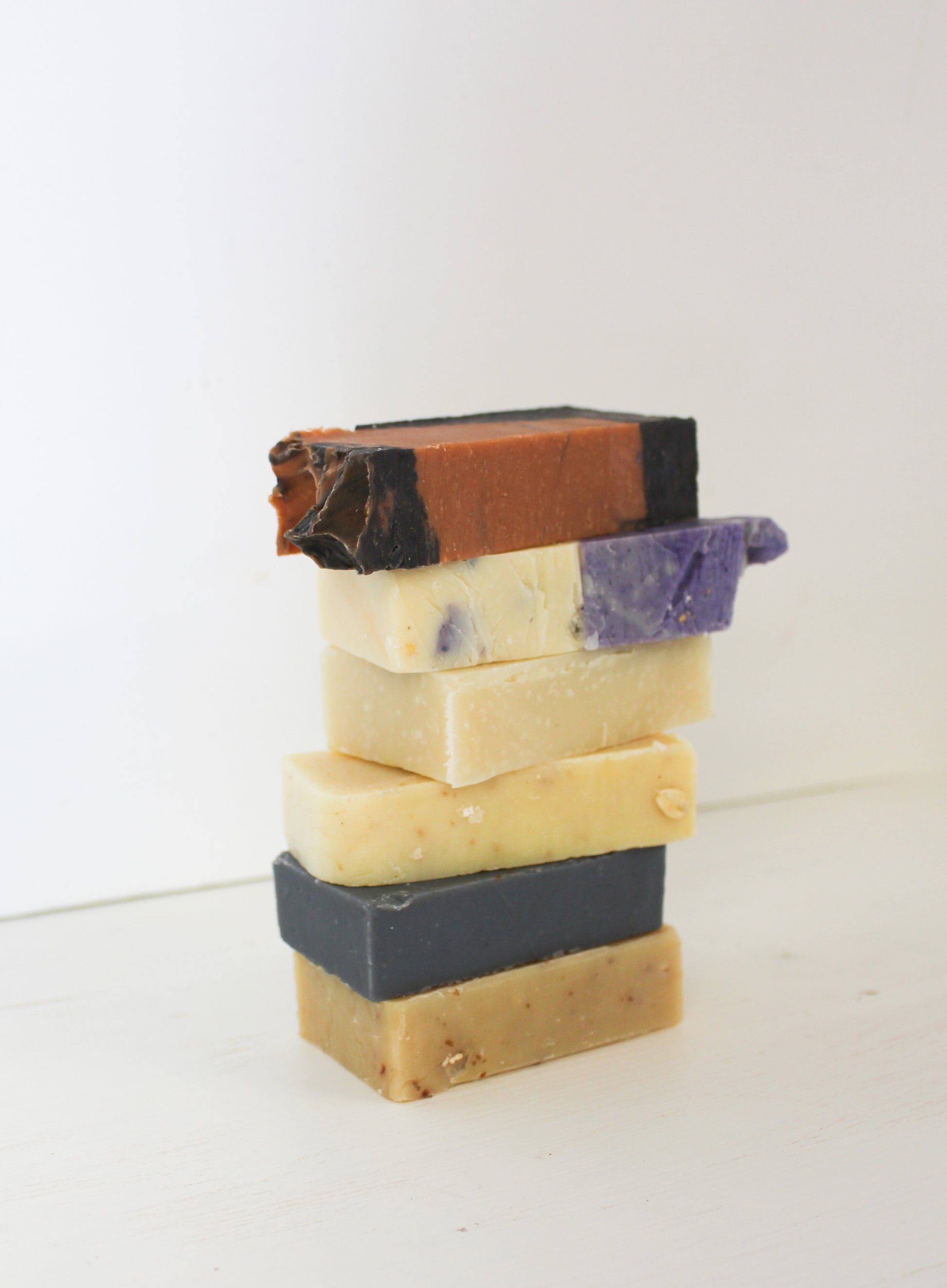 Stack of five different colored soap bars on a white background