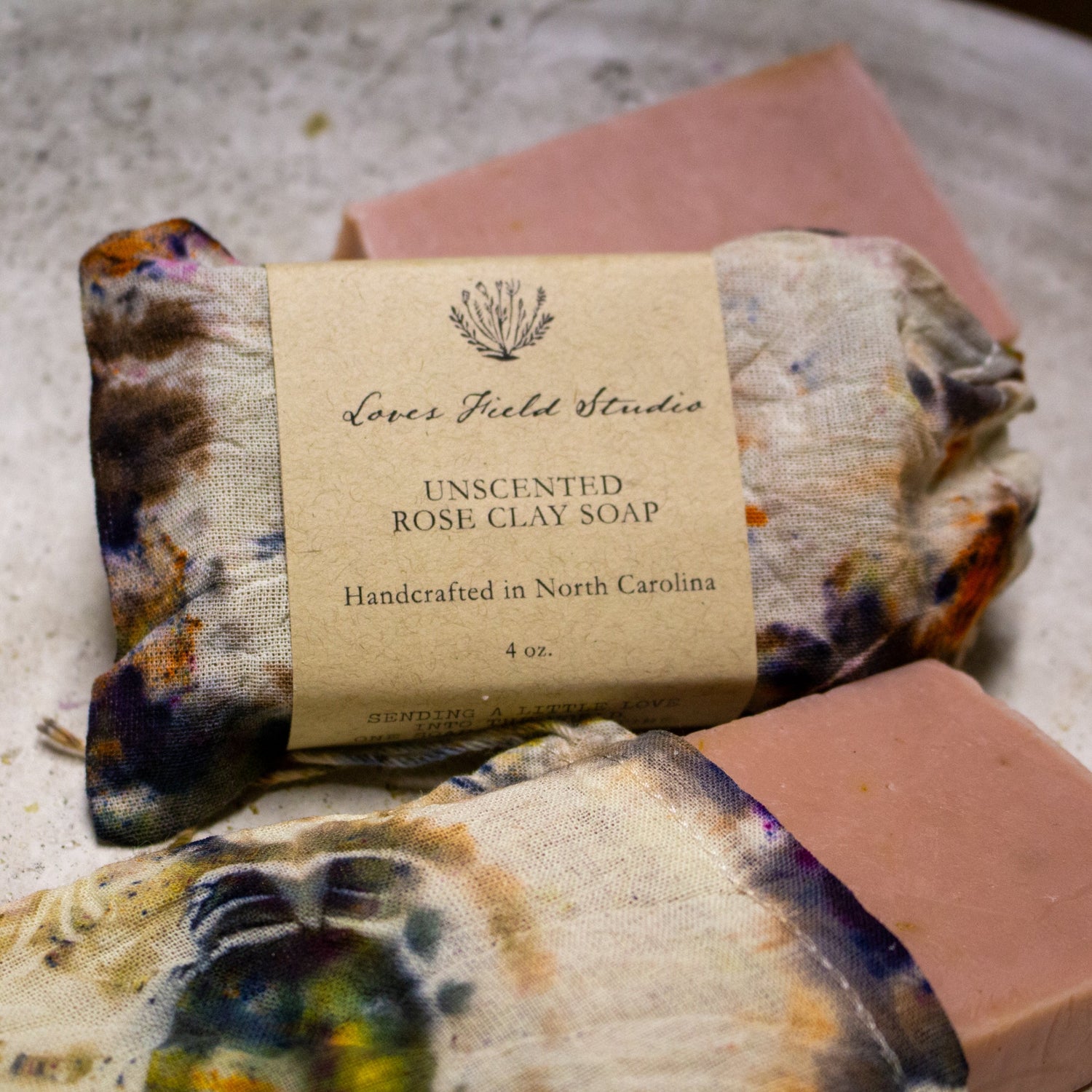 Handcrafted soap bar in a dyed soap bag, wrapped with a label on a textured surface